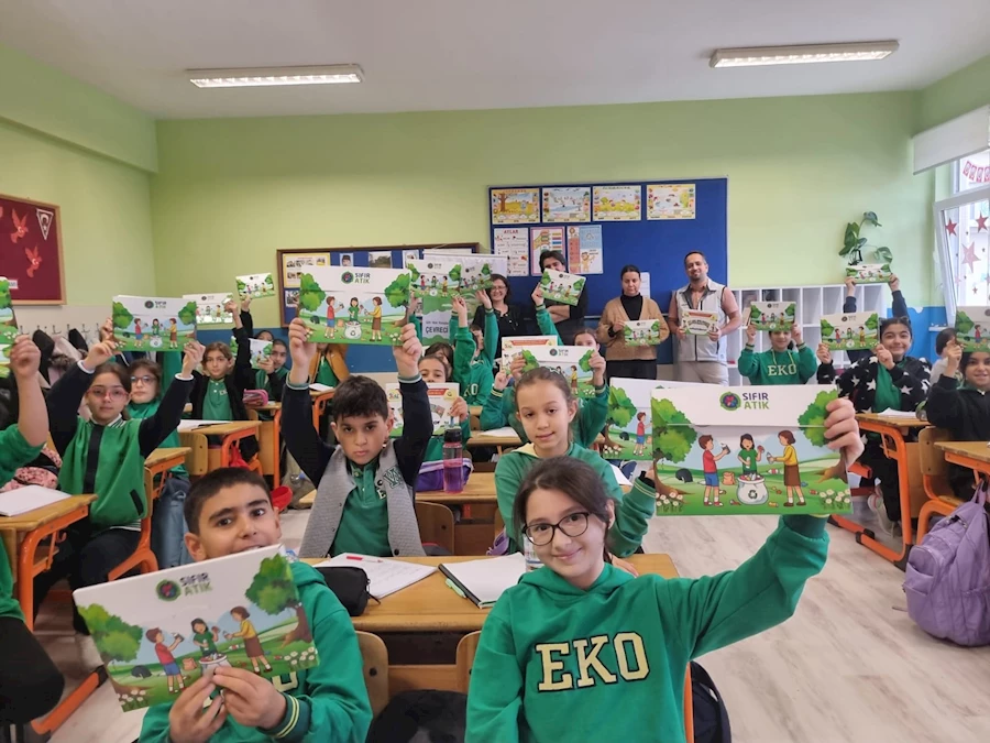 Sınıfta Sıfır Atık Eğitim Seti kitapçıklarını gururla kaldıran ilkokul öğrencileri, çevre bilinci ve geri dönüşüm farkındalığı kazanıyor.